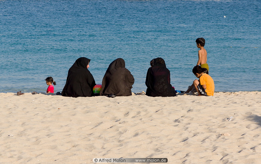 10 Iranian women with black chador on beach